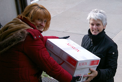 Mary Anne Beaudoin, coordinator of the campus effort for Adopt-a-Family, takes a box of goods from volunteer Debra Henderson